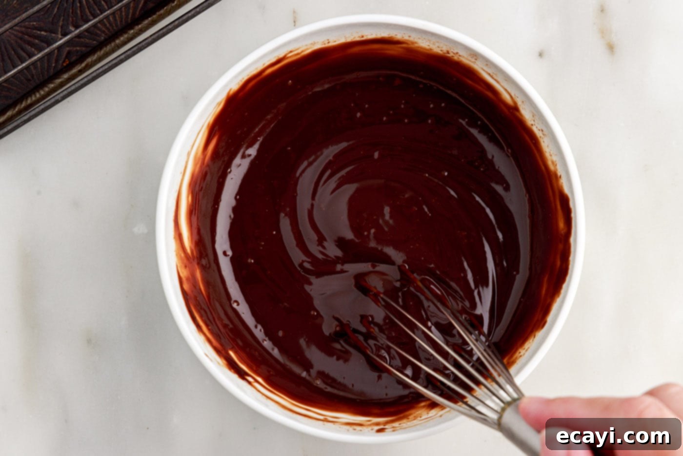 Velvet Chocolate Swirl 25 chocolate ganache in a bowl with a whisk