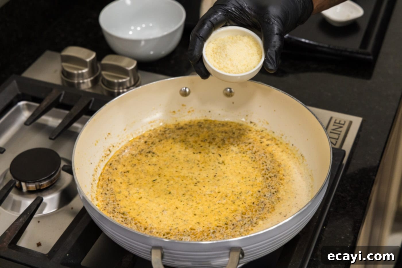Creamy Cajun Shrimp Pasta 12 Adding grated Parmesan cheese to the bubbling cream sauce in the skillet, ready to be whisked in.