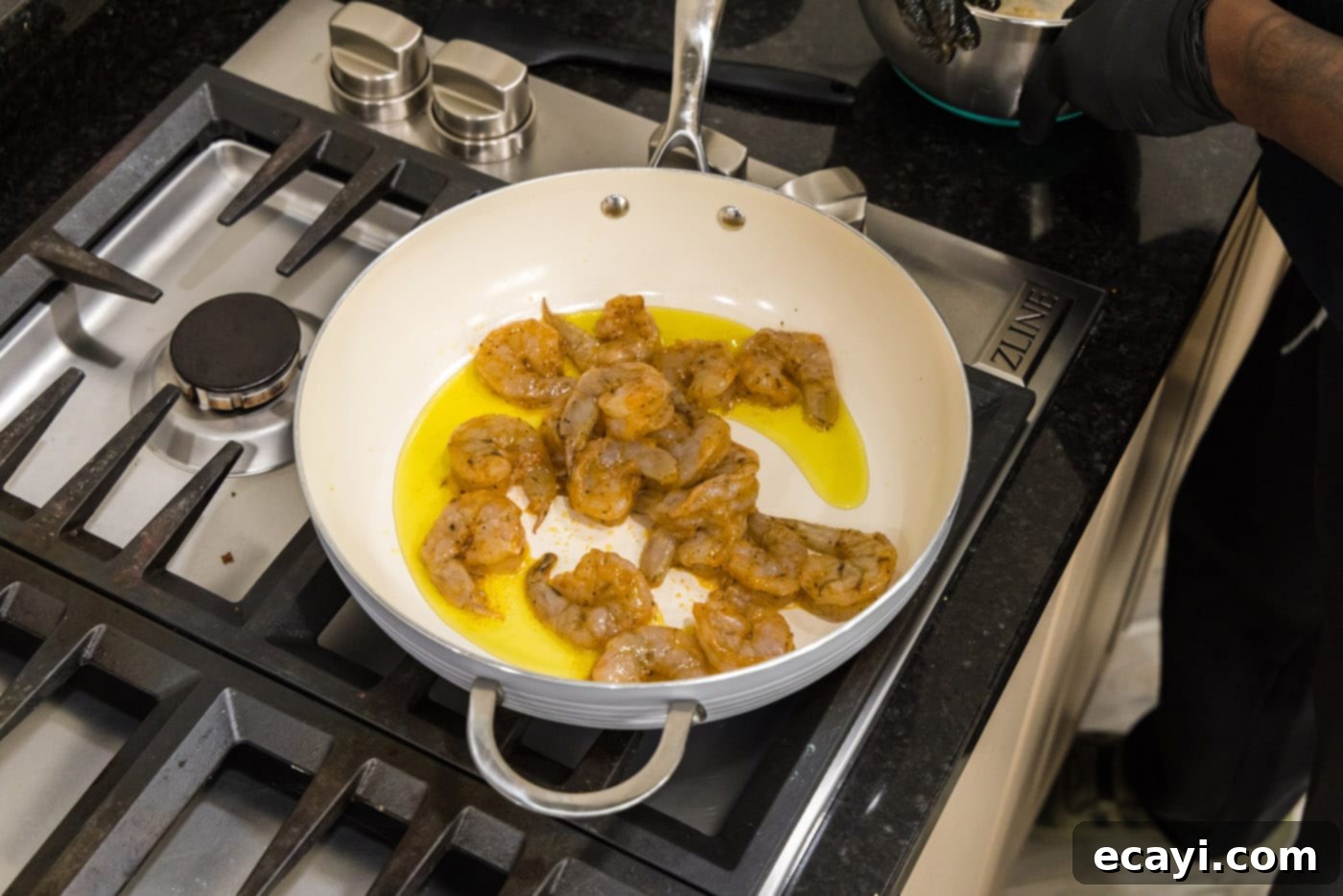 Creamy Cajun Shrimp Pasta 6 Raw, seasoned shrimp sizzling in a large deep-sided skillet with olive oil, beginning to cook.
