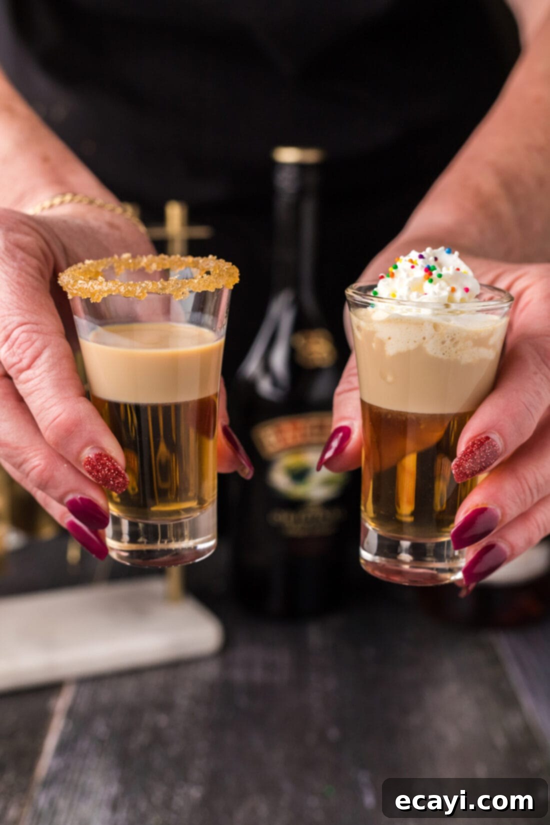 Buttery Nipple Bliss 2 Two Buttery Nipple Shots being held up in the air, showcasing their distinct layers