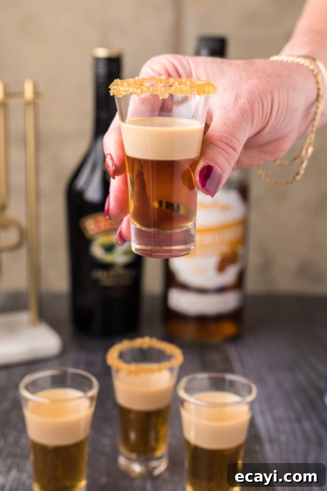 Buttery Nipple Bliss 11 A hand holding up a single Buttery Nipple Shot, showing its beautiful layers