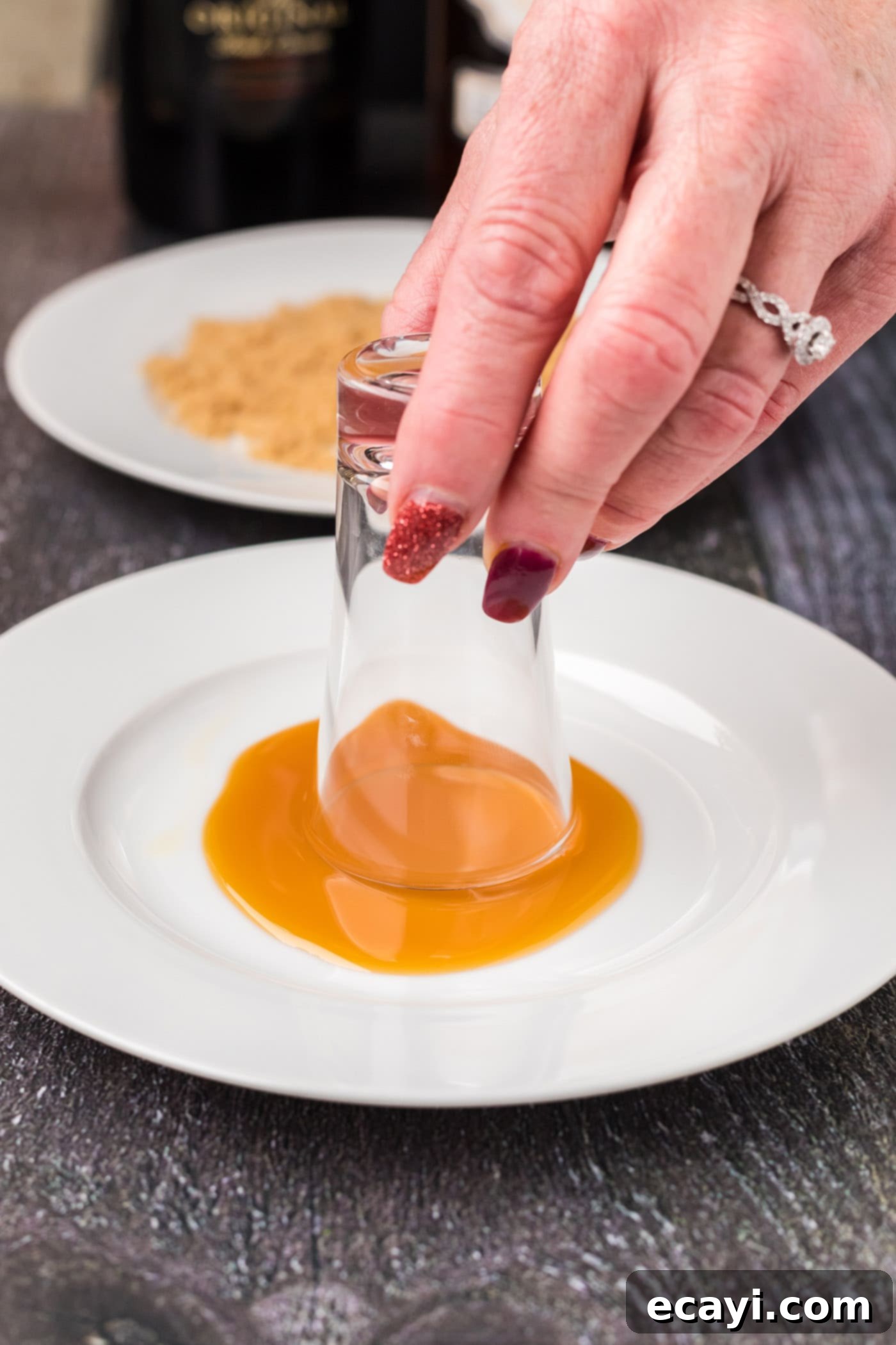Buttery Nipple Bliss 5 Dipping a shot glass into caramel sauce for rimming