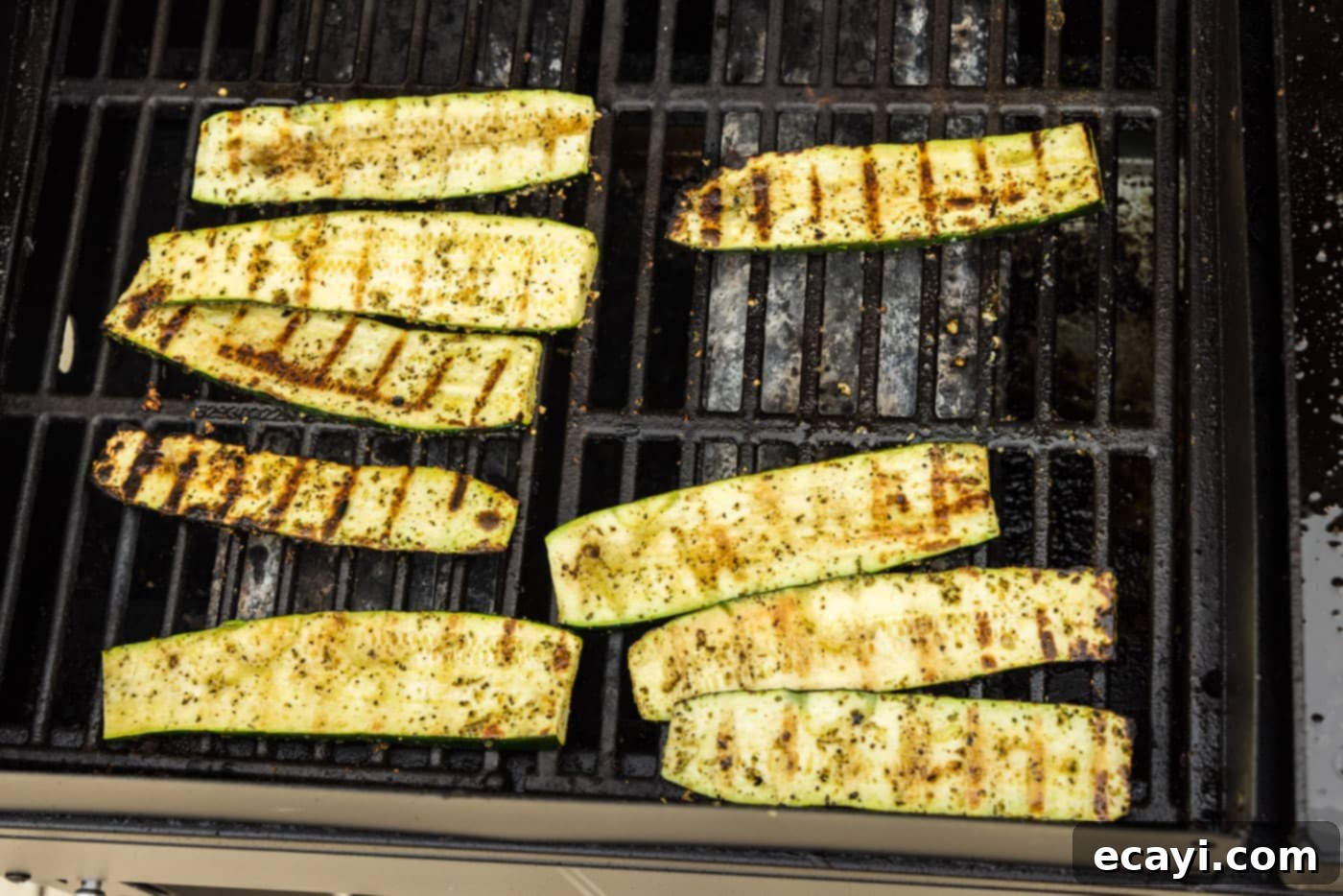 Smoky Zucchini Perfection 9 Close-up of zucchini slices with distinct char marks resting on the hot grill grates, indicating they are nearly cooked.