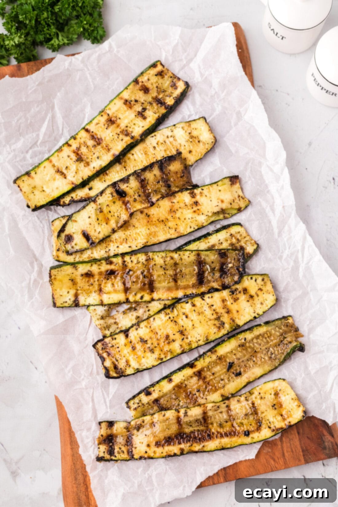 Smoky Zucchini Perfection 10 A rustic wooden platter with parchment paper holding freshly grilled zucchini, garnished with a light sprinkle of herbs.