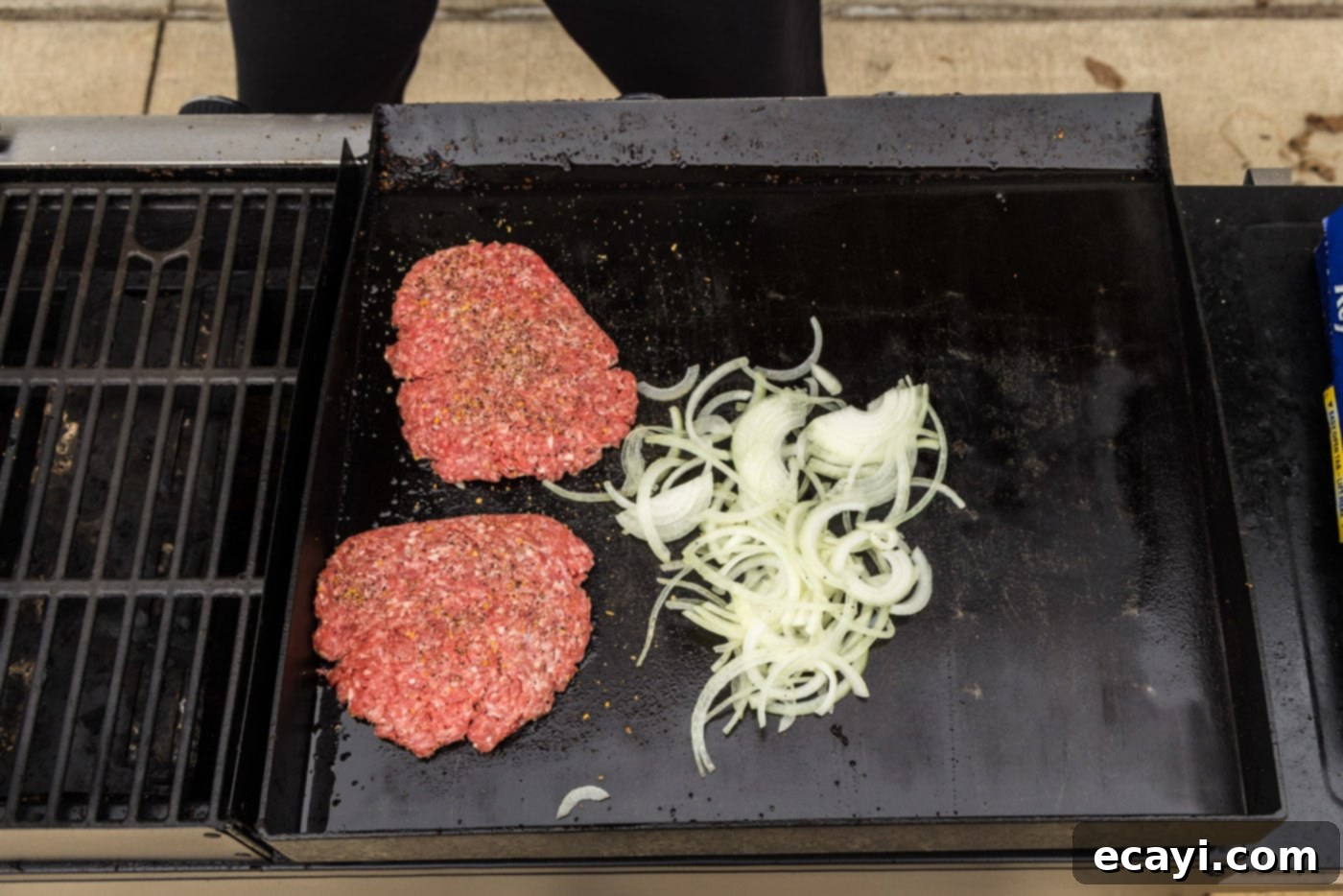 Patty Melt 11 sliced onions cooking next to burger patties on a grill