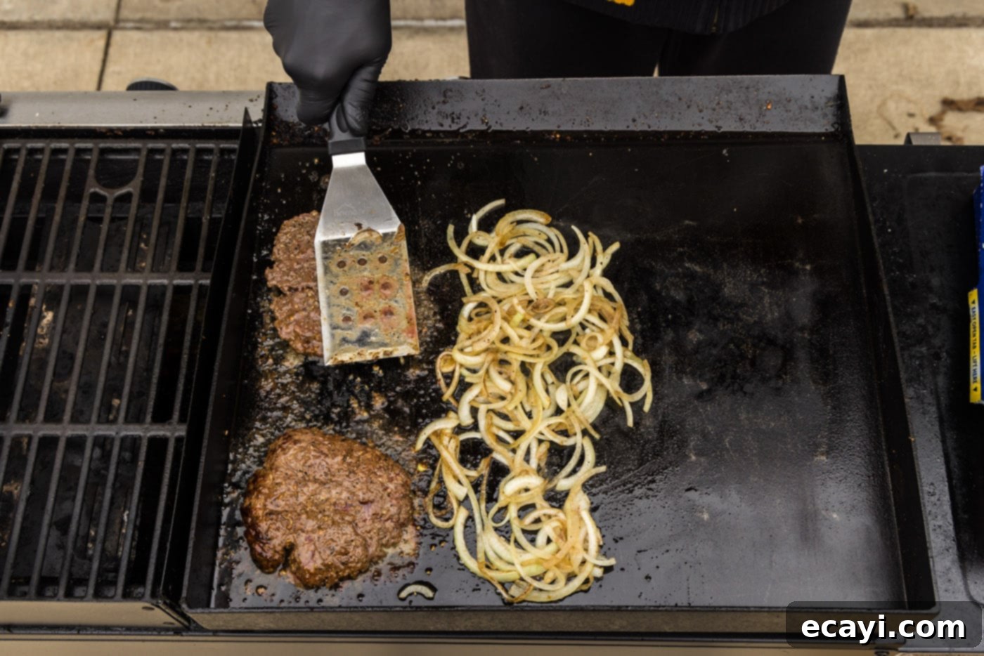 Patty Melt 12 cooked burger patties with caramellized onions on a grill