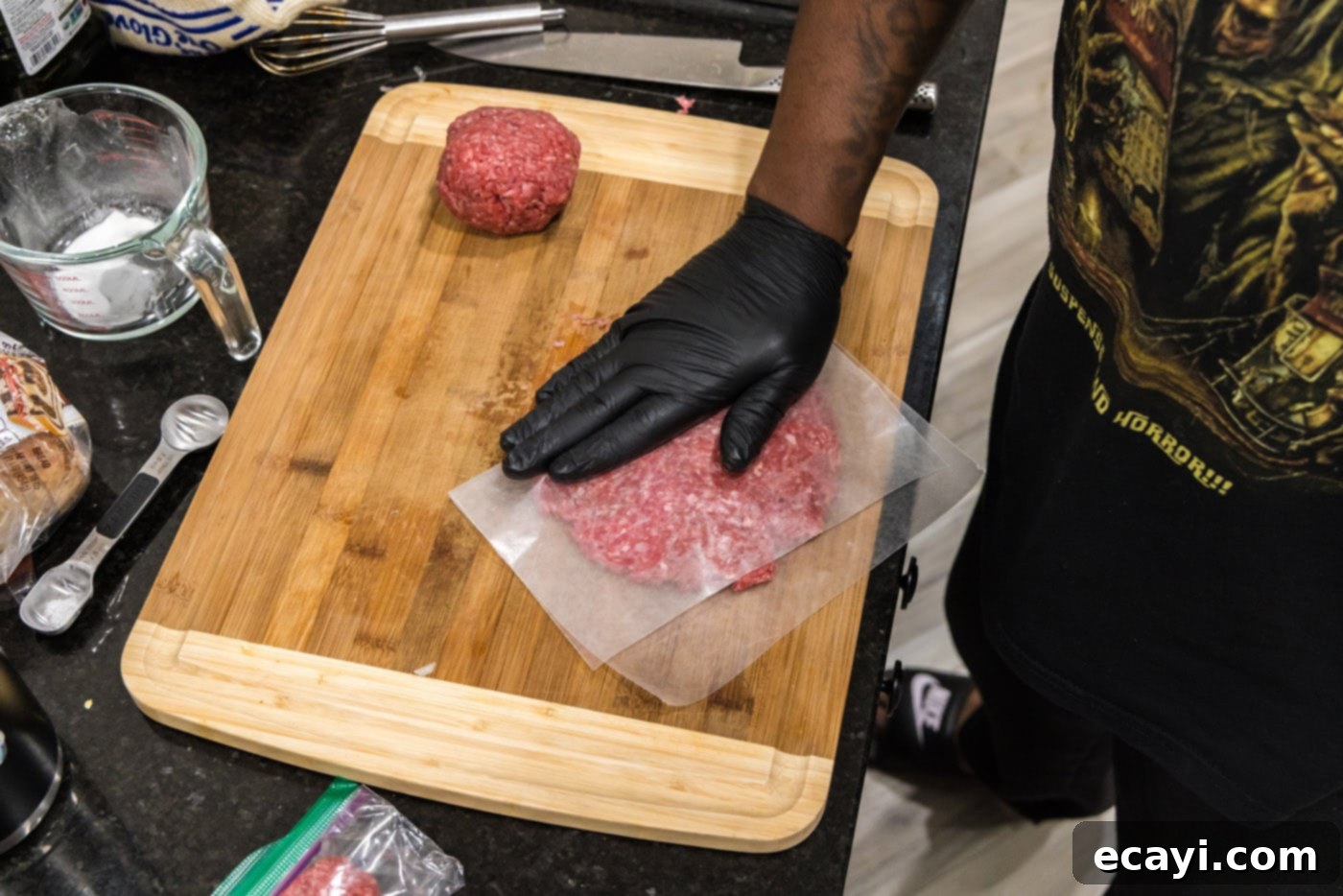 Patty Melt 6 pressing down on parchment covered burger meat to flatten