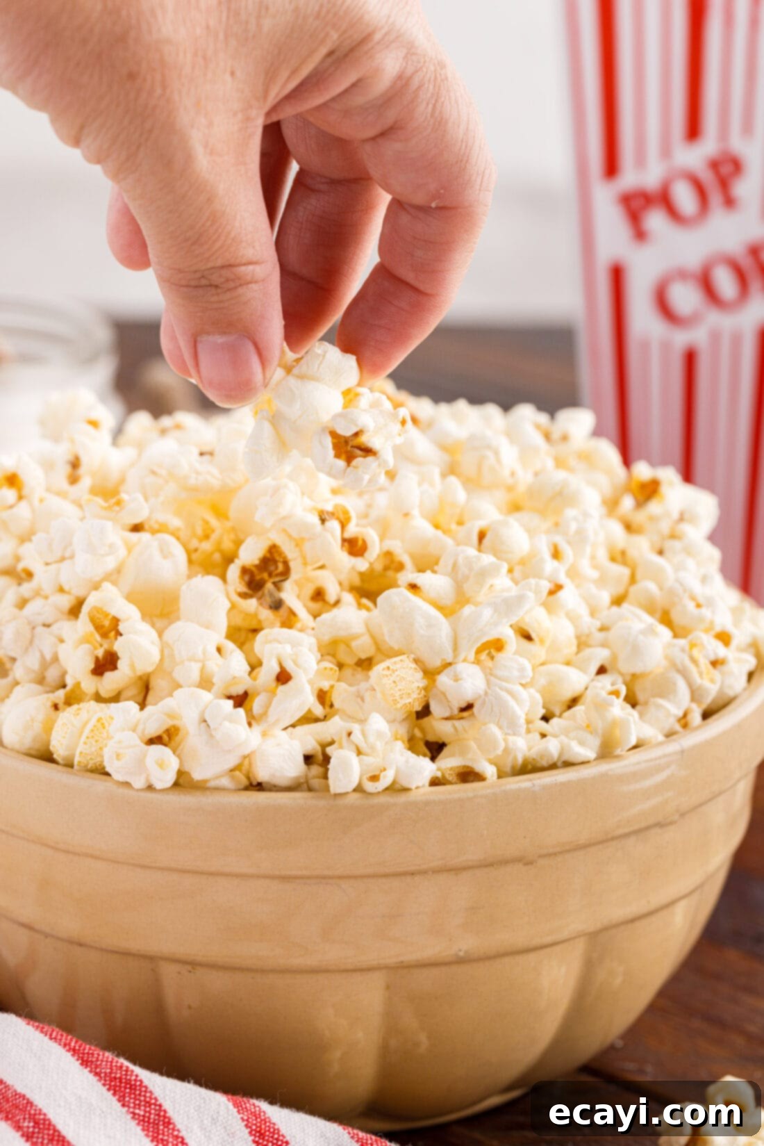 Irresistible Sweet & Salty Crunch 2 Hand reaching for freshly popped kettle corn in a serving bowl