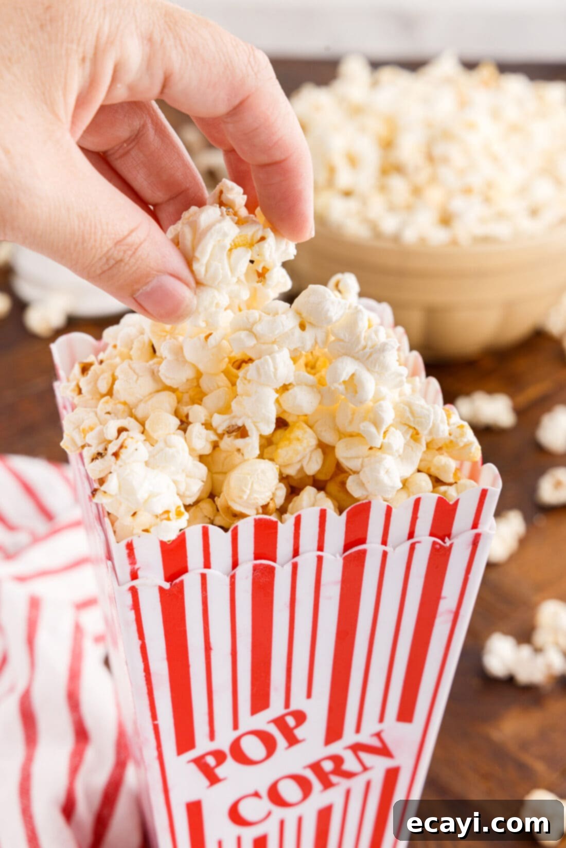 Irresistible Sweet & Salty Crunch 11 Hand scooping kettle corn from a striped popcorn bucket