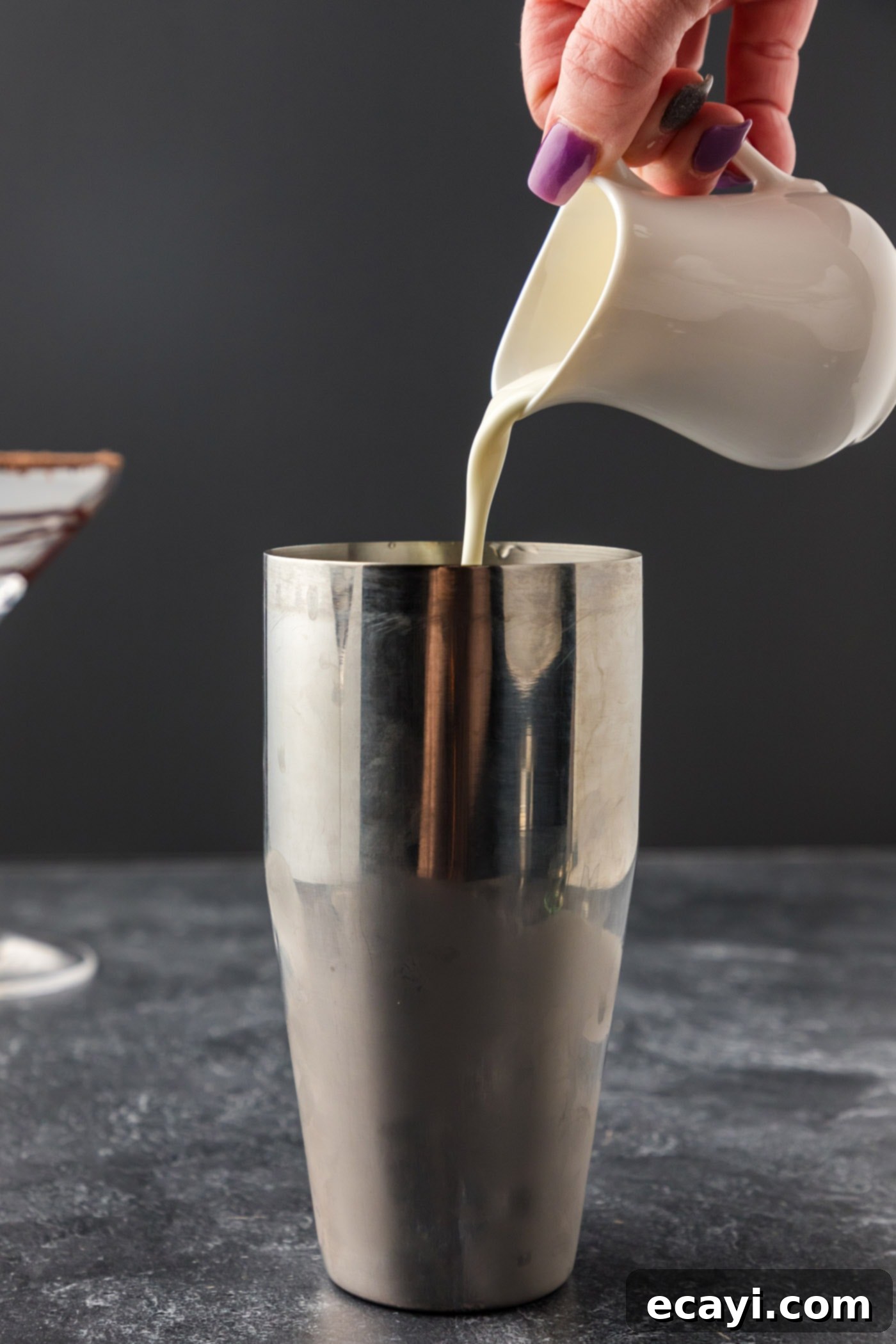 Velvet Grasshopper 10 pouring heavy cream into cocktail shaker with liqueurs and ice