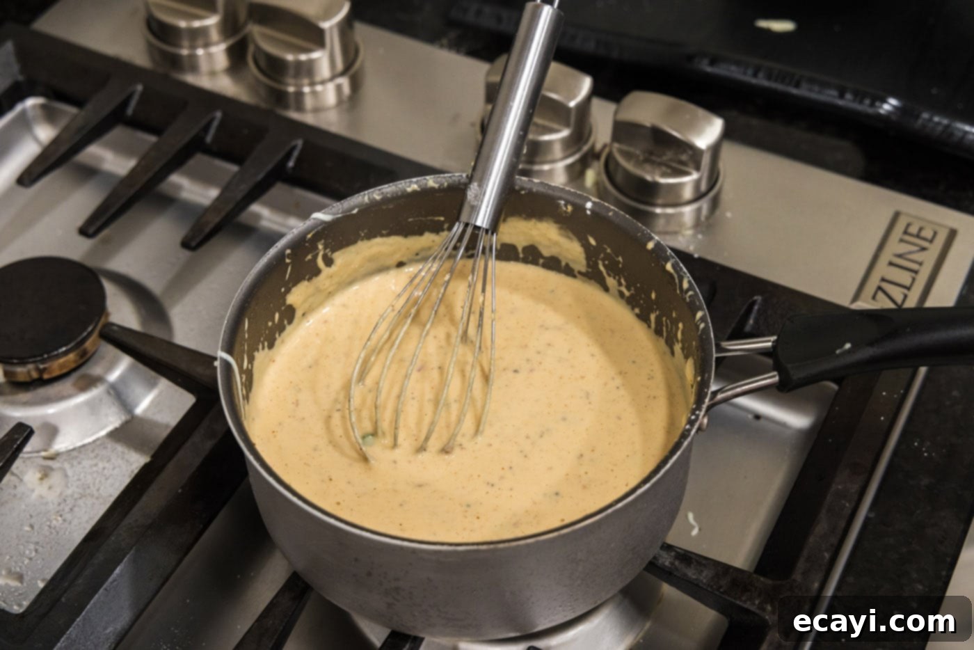 Creamy Queso 12 Whisking the cornstarch slurry into the queso dip in a saucepan to thicken it