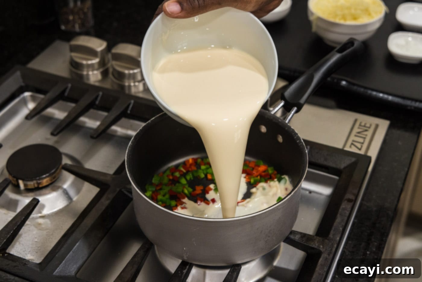 Creamy Queso 6 Pouring evaporated milk into a saucepan with peppers for queso base