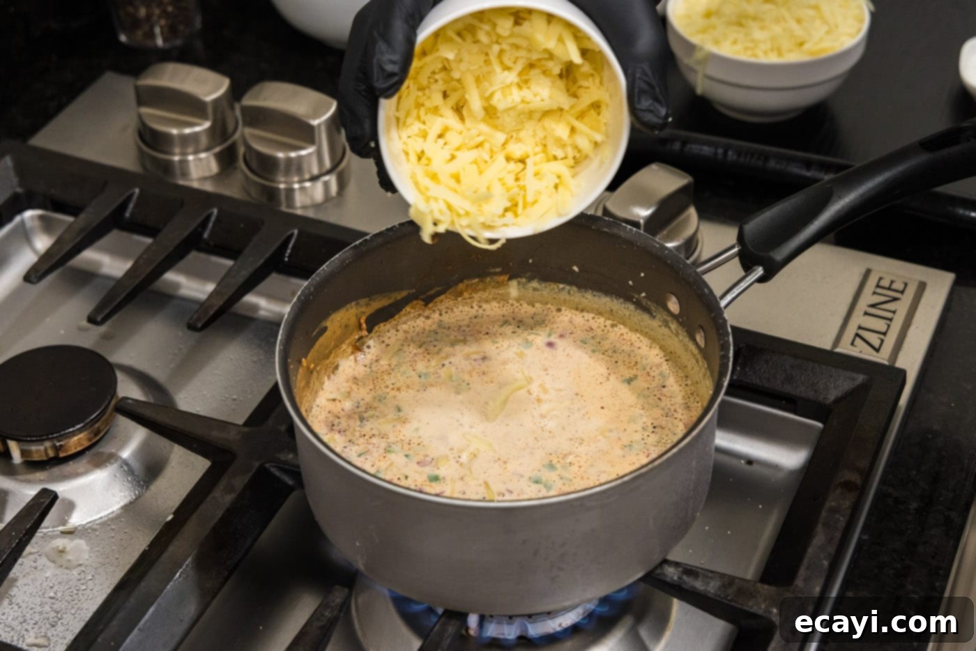 Creamy Queso 9 Adding shredded white cheddar cheese to the warm evaporated milk base for queso