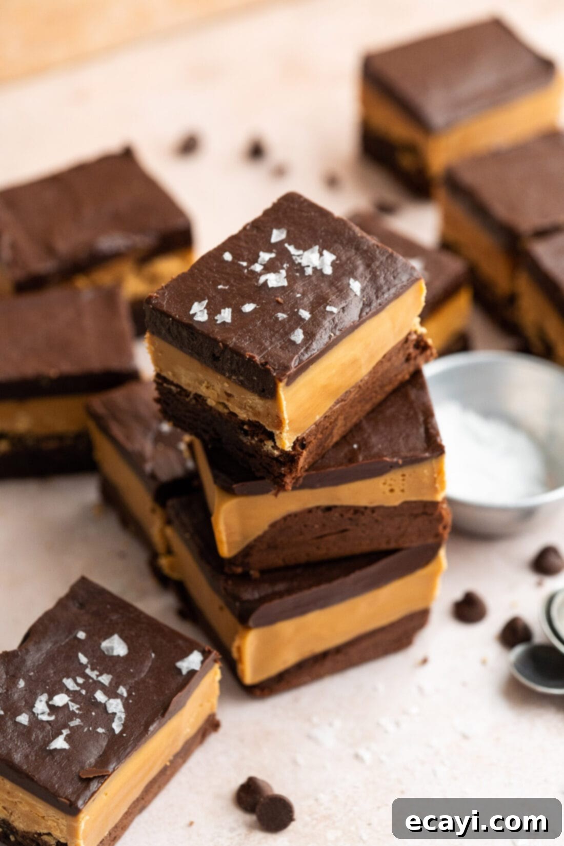 Decadent Millionaire Brownies 3 Stack of three Millionaire Brownies with other brownies scattered around, highlighting their layered beauty.