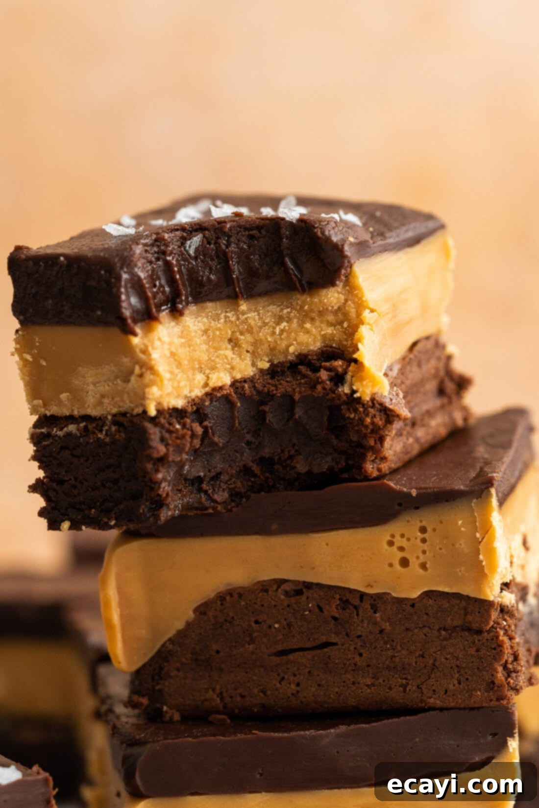 Decadent Millionaire Brownies 21 Close up photo of a Millionaire Brownie with a bite taken out, showing the perfect layers and rich texture.