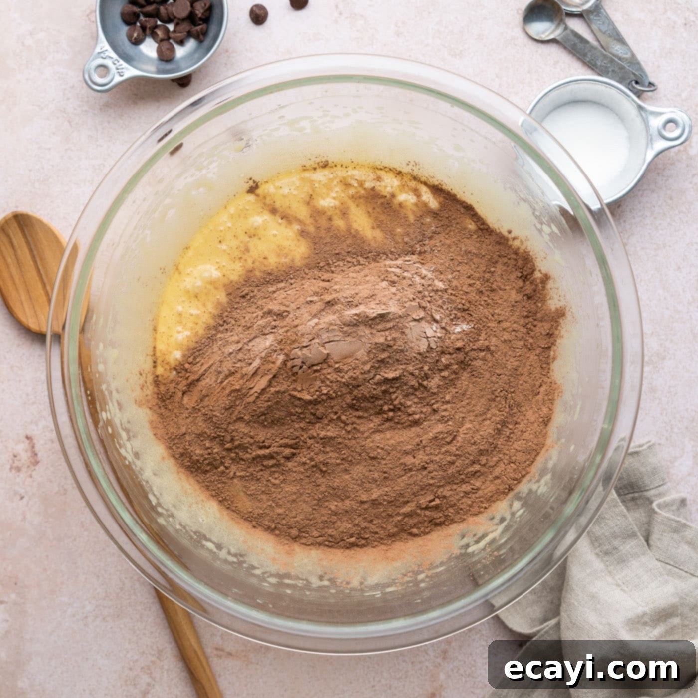 Decadent Millionaire Brownies 10 Adding dry ingredients (flour, cocoa, salt) to the wet brownie batter in a bowl.