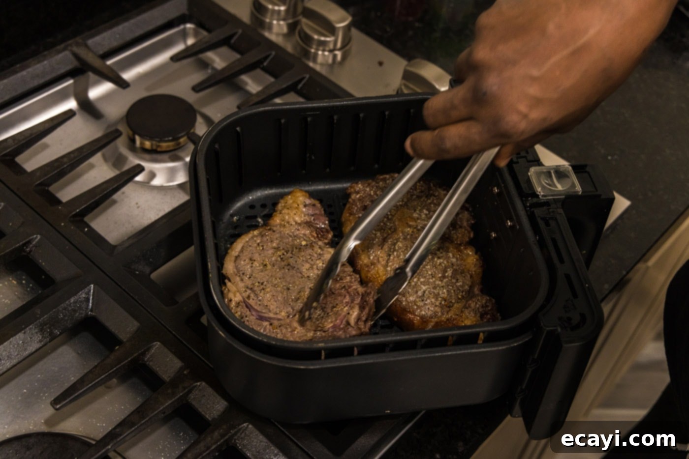 Restaurant-Quality Air Fryer Steak 7 Flipping steaks in the air fryer basket for even cooking.