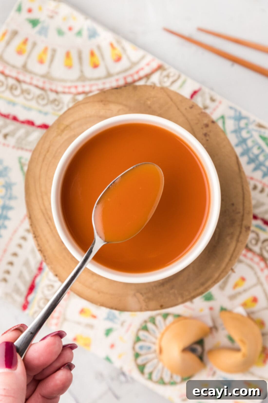 Zesty Sweet Fusion 2 Spoonful of Sweet and Sour Sauce held over a bowl of Sweet and Sour Sauce