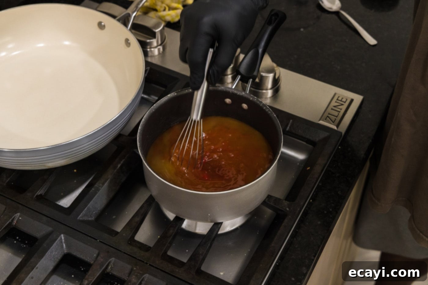 Zesty Sweet Fusion 5 whisking sweet and sour sauce in a saucepan