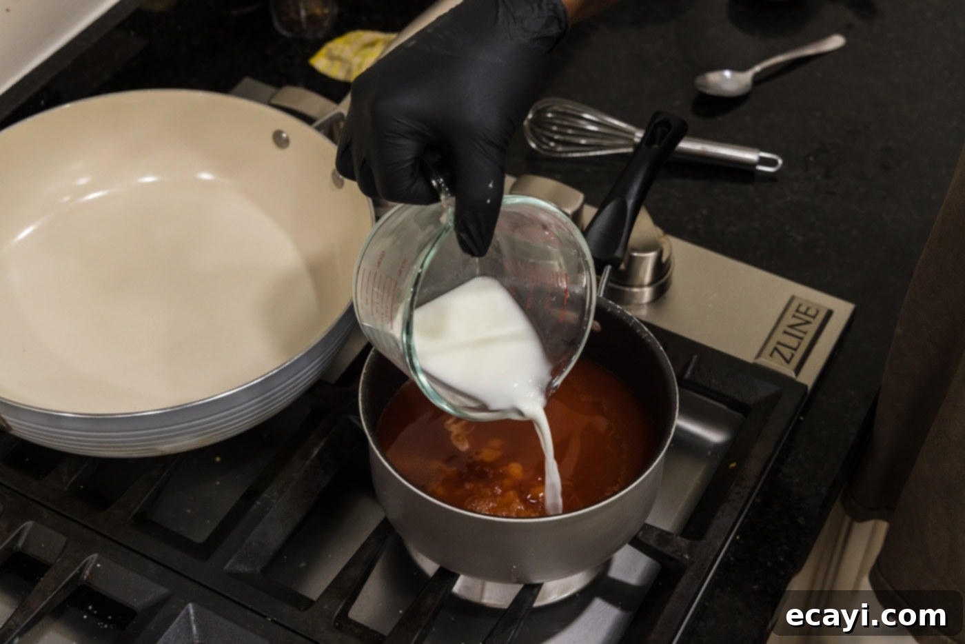 Zesty Sweet Fusion 6 pouring cornstarch slurry into saucepan with sweet and sour sauce