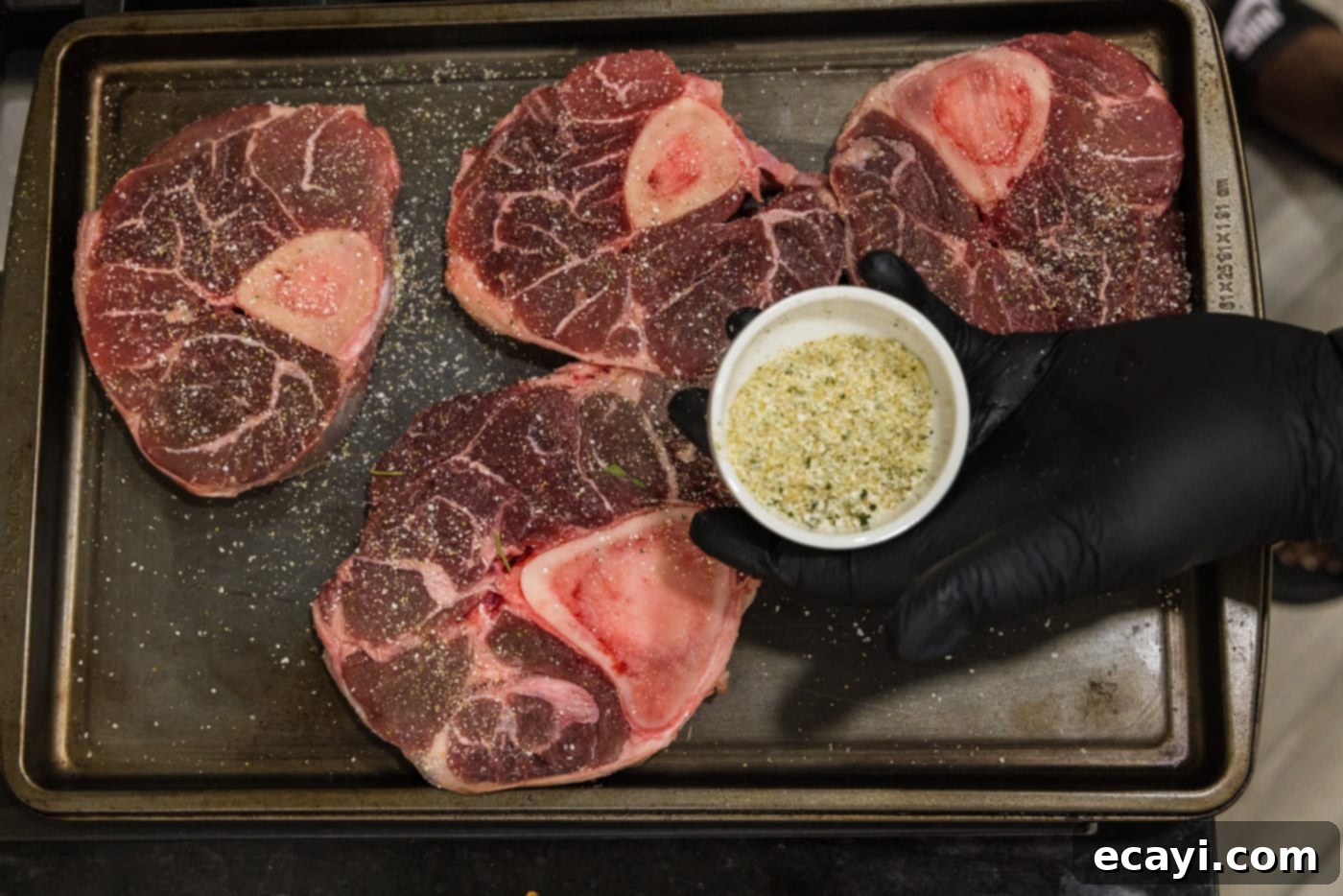 Melt-in-Your-Mouth Braised Beef Shanks 5 Seasoning raw beef shanks with garlic salt on a cutting board