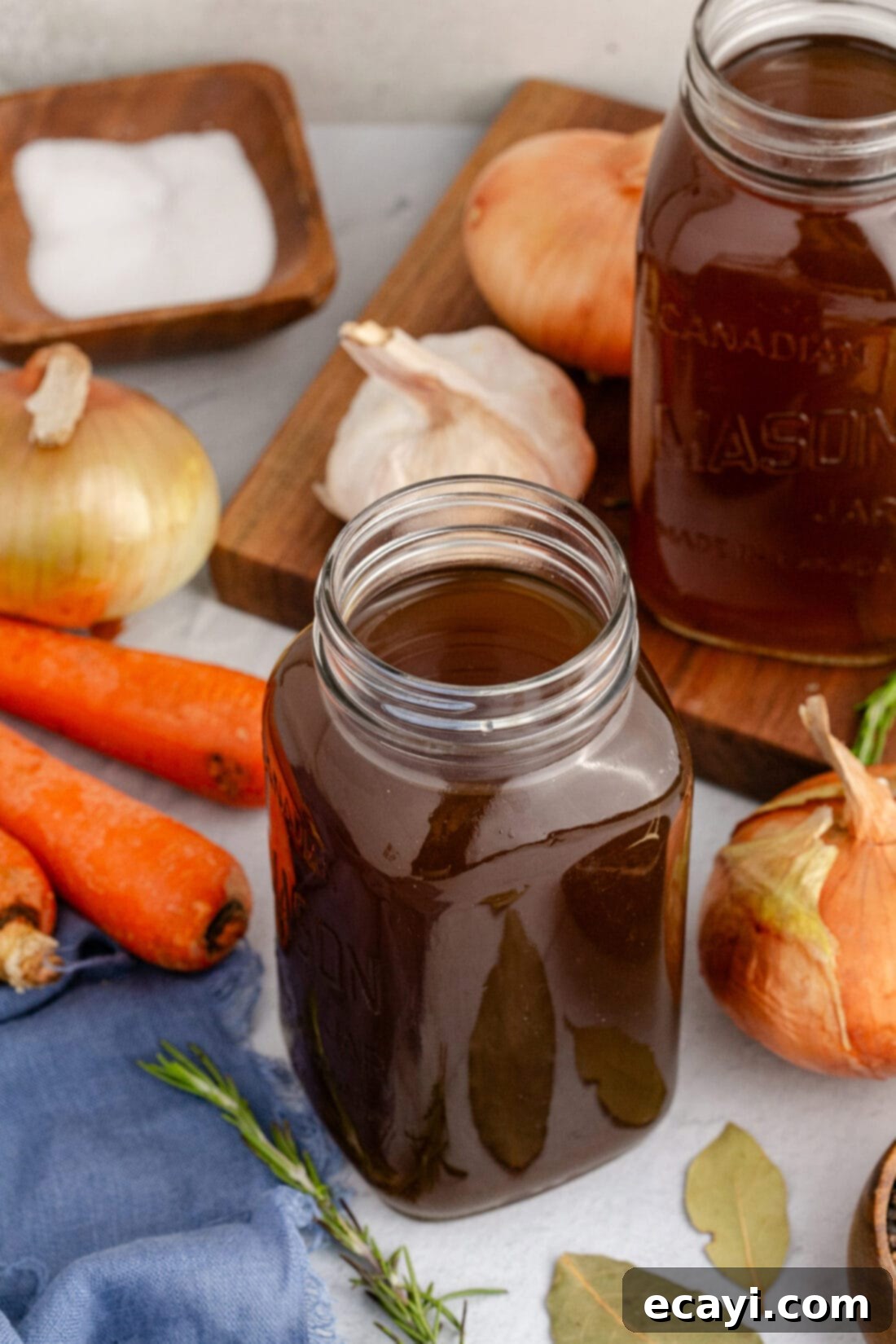 Garden Elixir 2 Jar of Vegetable Broth with fresh vegetables in the background, including carrots, celery, and herbs