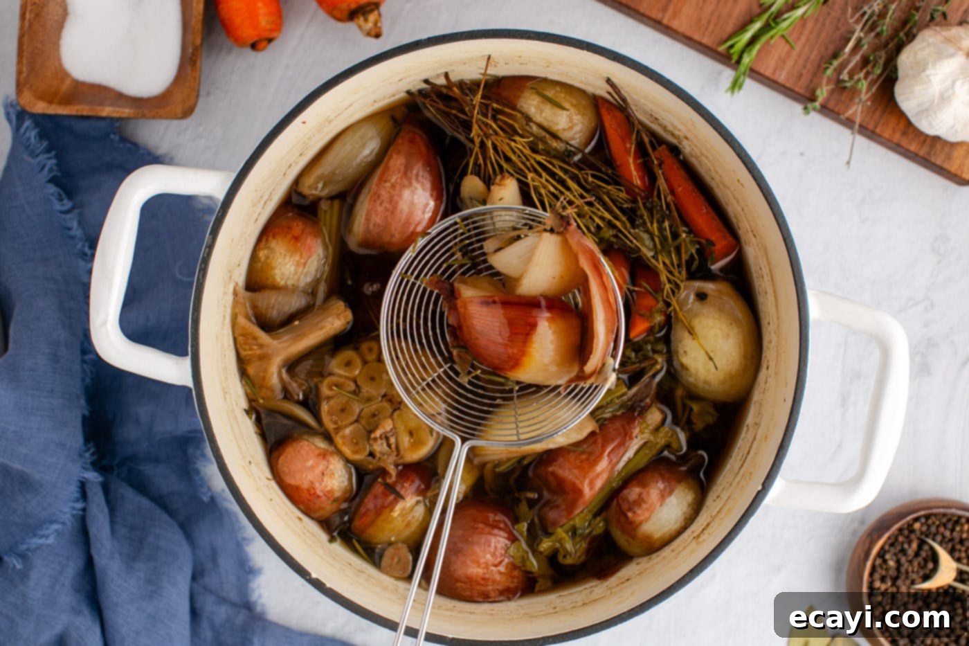 Garden Elixir 9 A slotted spoon removing large pieces of cooked vegetables and herbs from the stockpot of broth