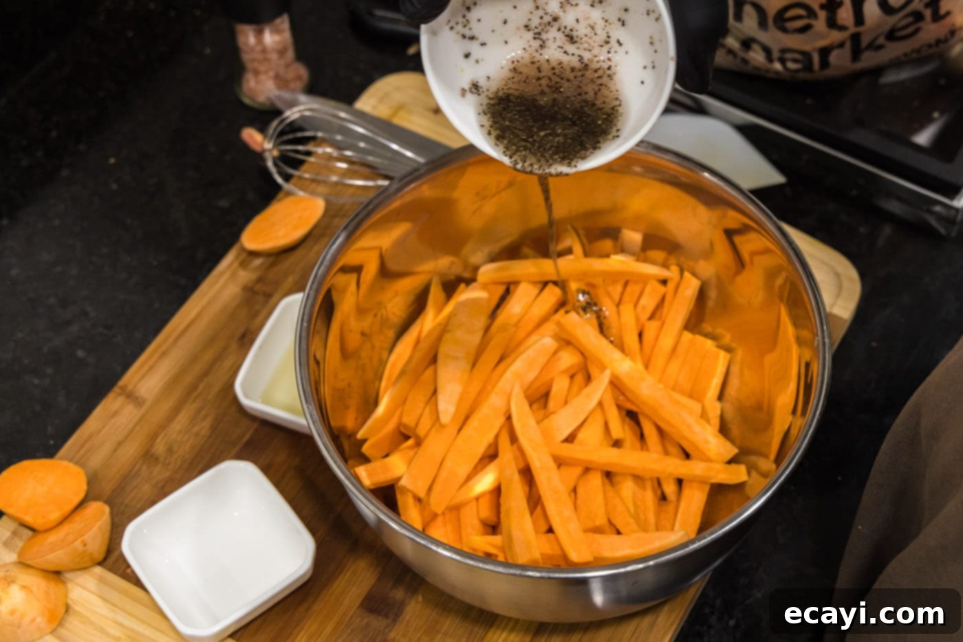 Perfectly Crispy Air Fryer Sweet Potato Fries 9 Pouring the olive oil, salt, and pepper mixture over the cut sweet potato fries