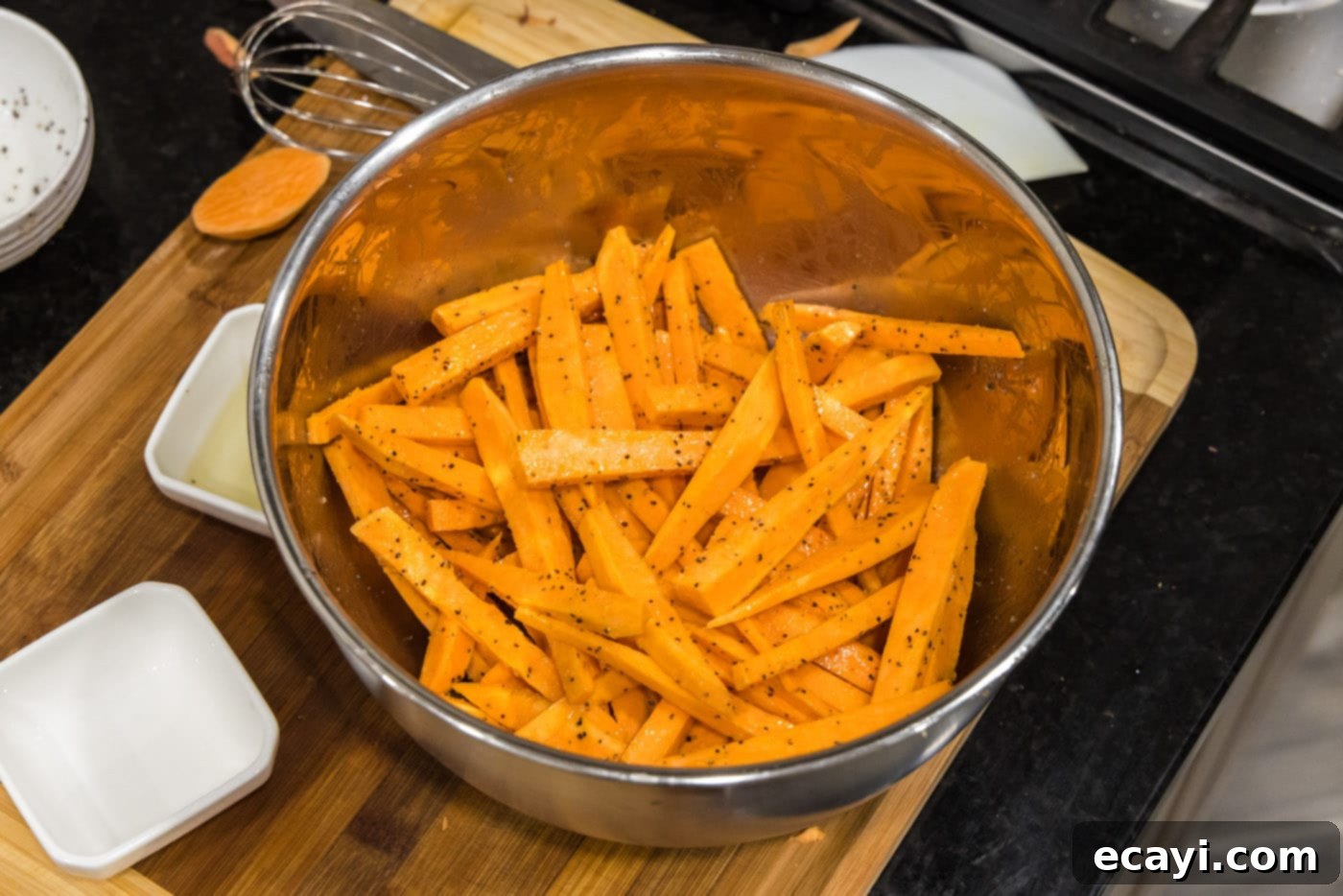 Perfectly Crispy Air Fryer Sweet Potato Fries 10 Sweet potato fries being tossed in oil and seasonings, showing an even coat