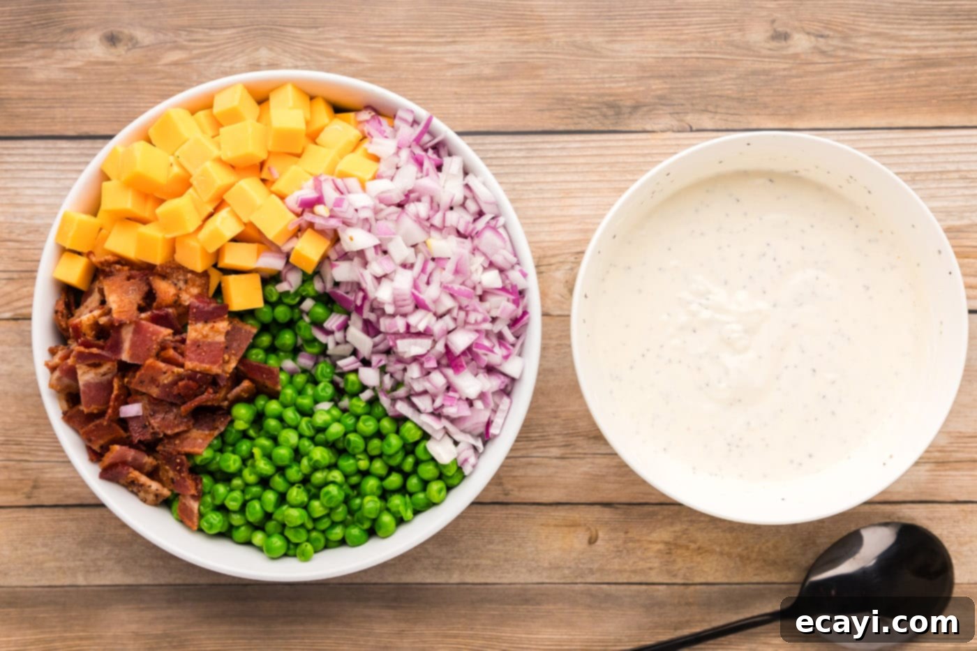 Refreshing Creamy Pea Salad 8 All the main pea salad ingredients, including peas, red onion, bacon, and cheddar, in a large bowl next to the prepared dressing.