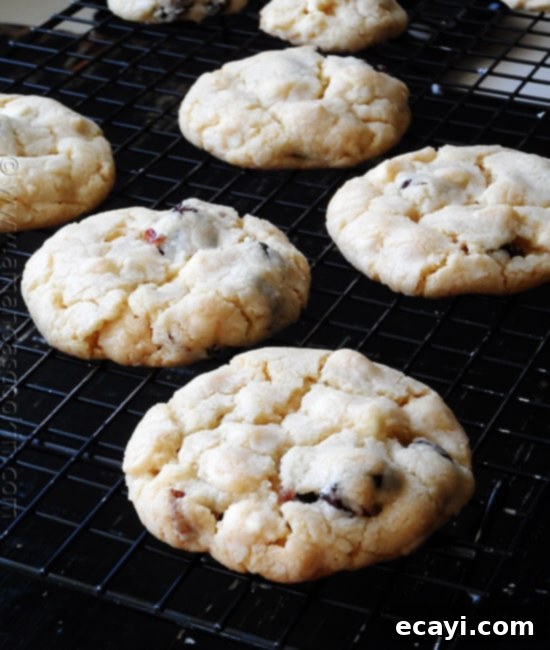Ruby Red White Chocolate Delights 3 A close up photo of cherry white chocolate chip cookies resting on a cooling rack.