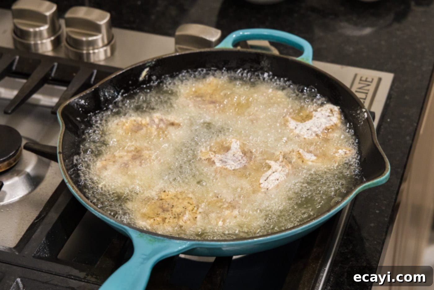 Southern Comfort Bliss 13 Crispy dredged chicken frying in hot oil in a skillet
