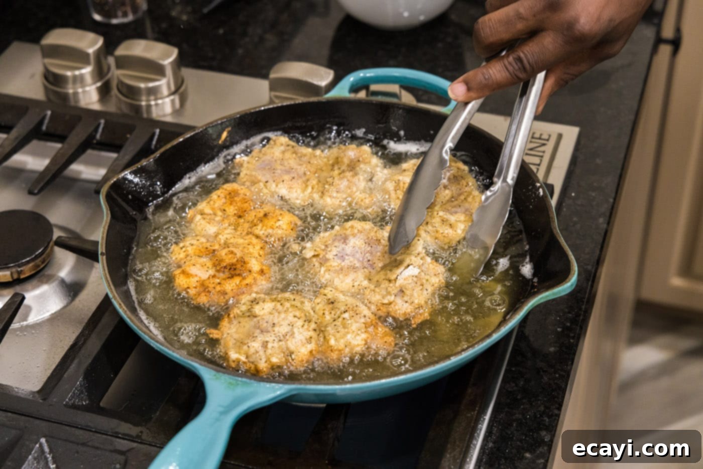 Southern Comfort Bliss 14 Tongs flipping golden-brown fried chicken in a skillet