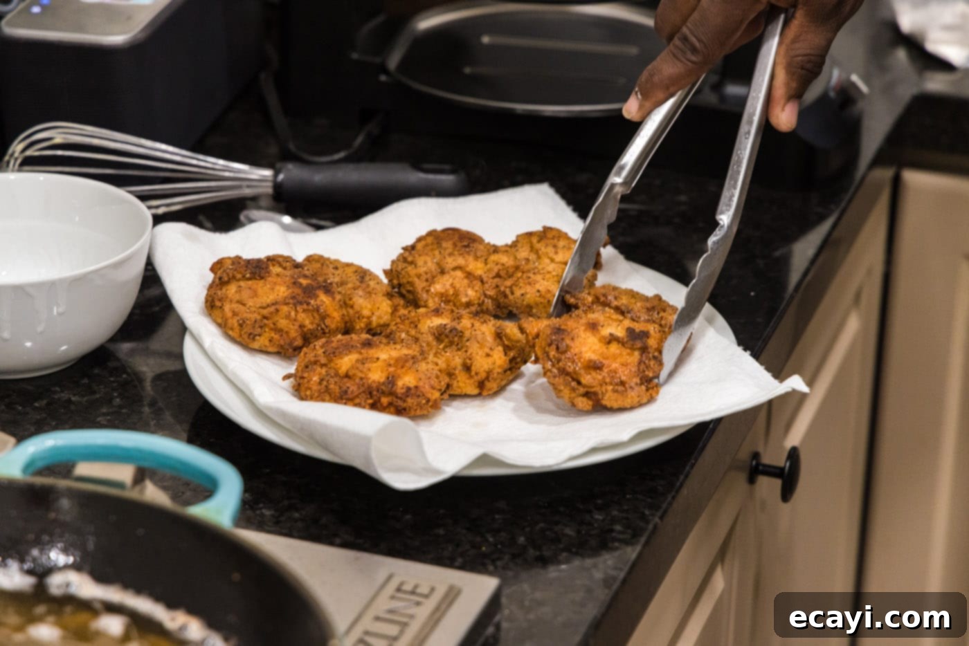 Southern Comfort Bliss 16 Crispy fried boneless chicken thighs resting on a paper towel-lined plate to drain excess oil