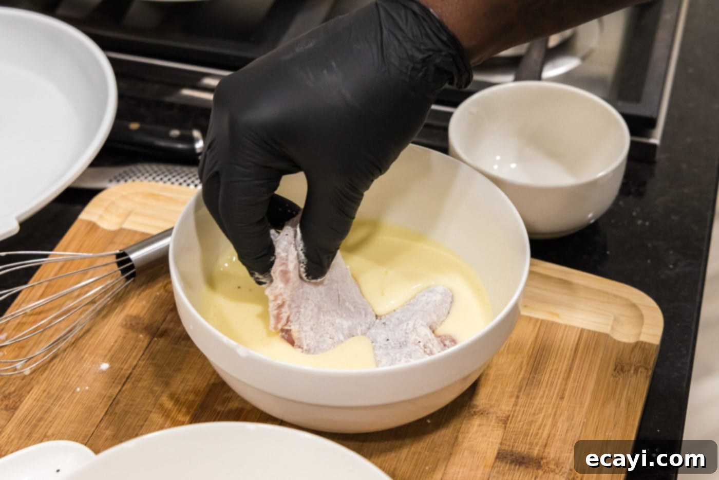 Southern Comfort Bliss 9 Flour-coated chicken being dipped into the egg and buttermilk mixture