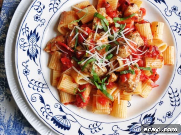Spiced Chicken and Mezzi Rigatoni 6 An overhead of a plate of spiced chicken and mezzi rigatoni topped with grated Parmigiano-Reggiano cheese and fresh basil.