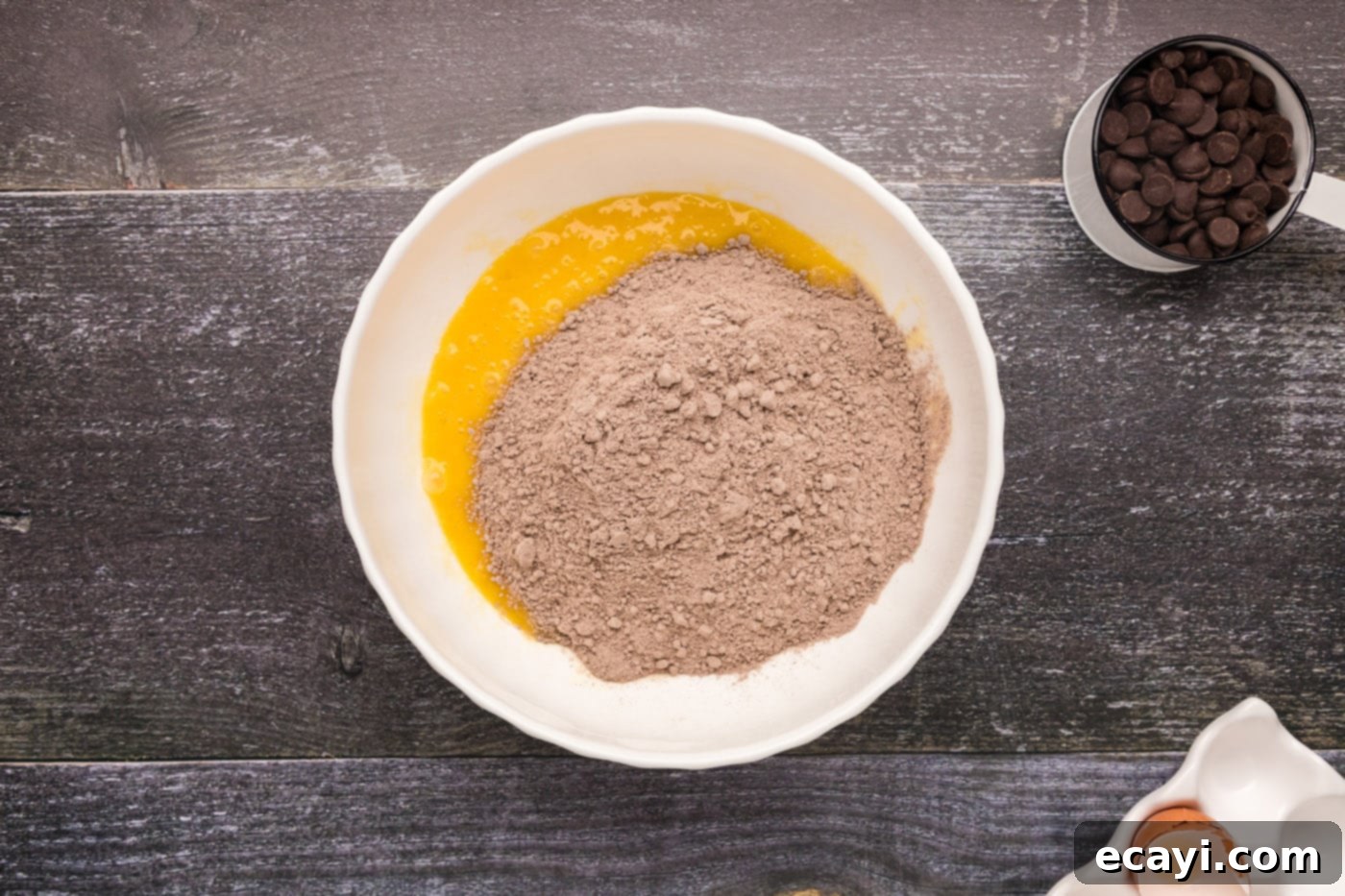 Foolproof Cake Mix Brownies 7 dry cake mix being added to the whisked wet ingredients in a large bowl