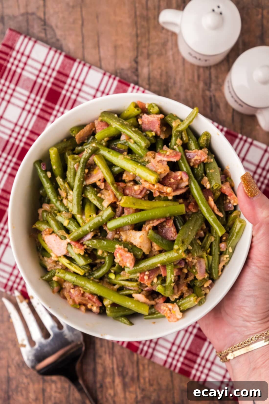 Homestyle Southern Green Beans 2 Hand holding a bowl of Southern Green Beans with tender beans, bacon, and shallots