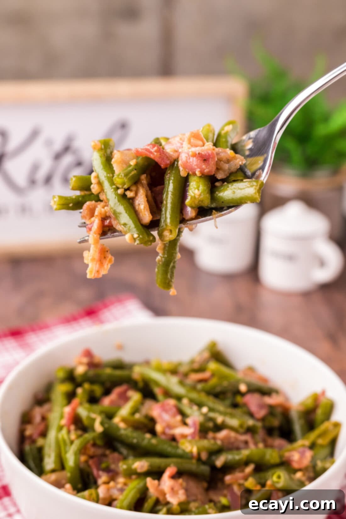 Homestyle Southern Green Beans 3 Fork lifting tender Southern Green Beans with bacon and shallots from a bowl