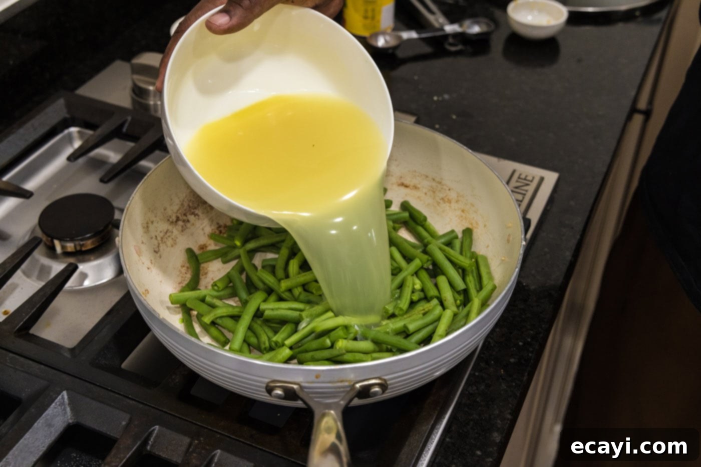 Homestyle Southern Green Beans 8 Pouring chicken stock into a skillet with fresh green beans and bacon fat