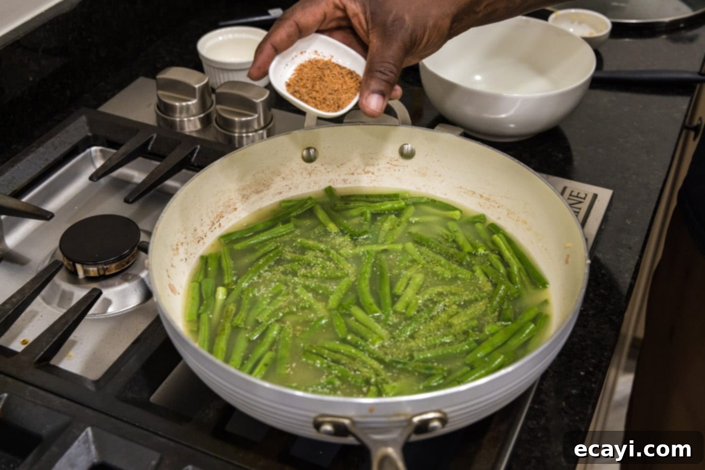 Homestyle Southern Green Beans 9 Adding Cajun seasoning to green beans simmering in a skillet