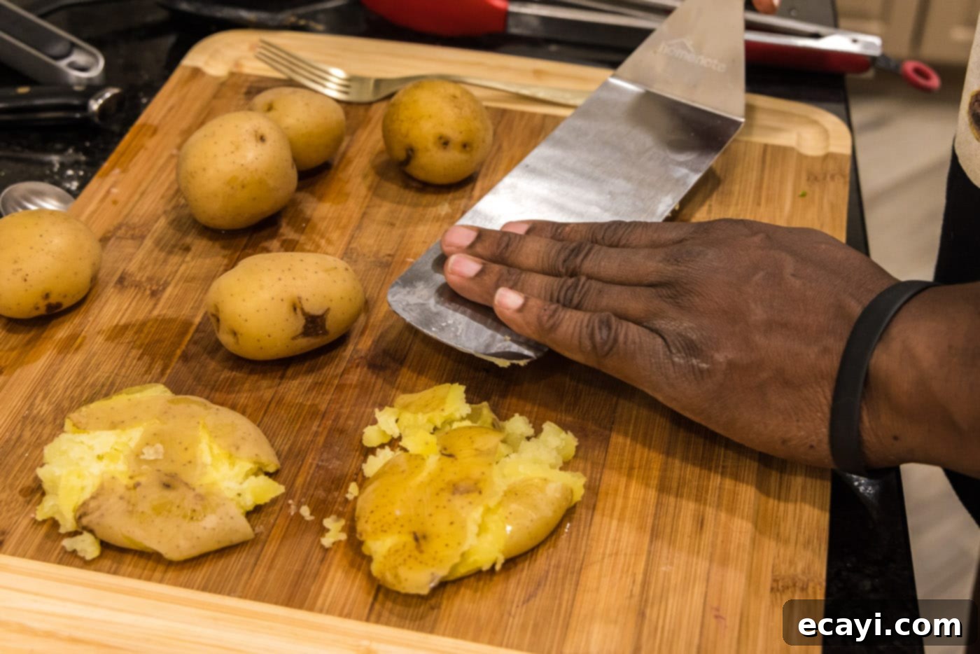 Crispy Smashed Spuds 7 smashing yukon gold potatoes with a spatula on a cutting board