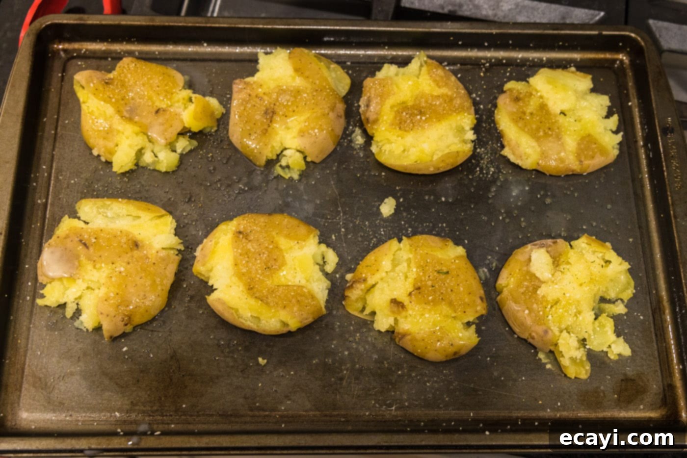 Crispy Smashed Spuds 10 seasoned and butter basted smashed potatoes on a baking sheet, ready for baking