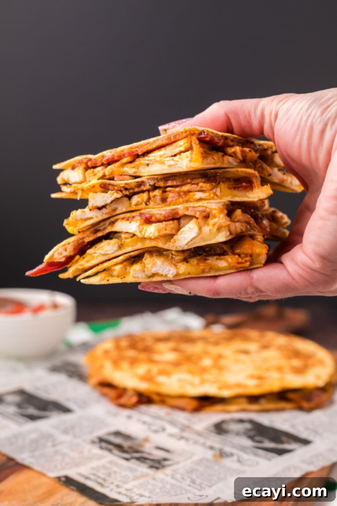 Ultimate Chicken Bacon Ranch Quesadillas 3 A hand holding up a freshly made, golden-brown Chicken Bacon Ranch Quesadilla, showcasing its savory fillings.