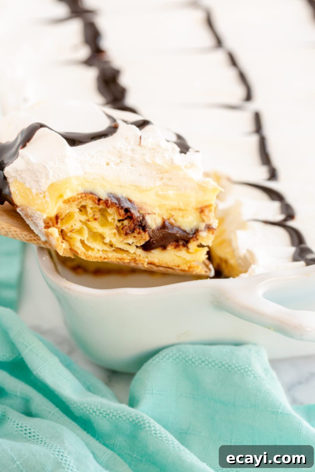 Ultimate Chocolate Eclair Puff Cake 2 removing a slice of Cream Puff Chocolate Eclair Cake from pan
