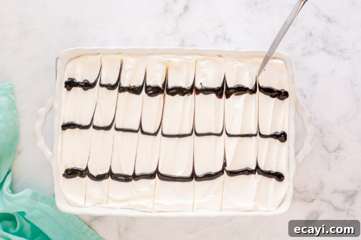 Ultimate Chocolate Eclair Puff Cake 11 using a knife to drag chocolate lines