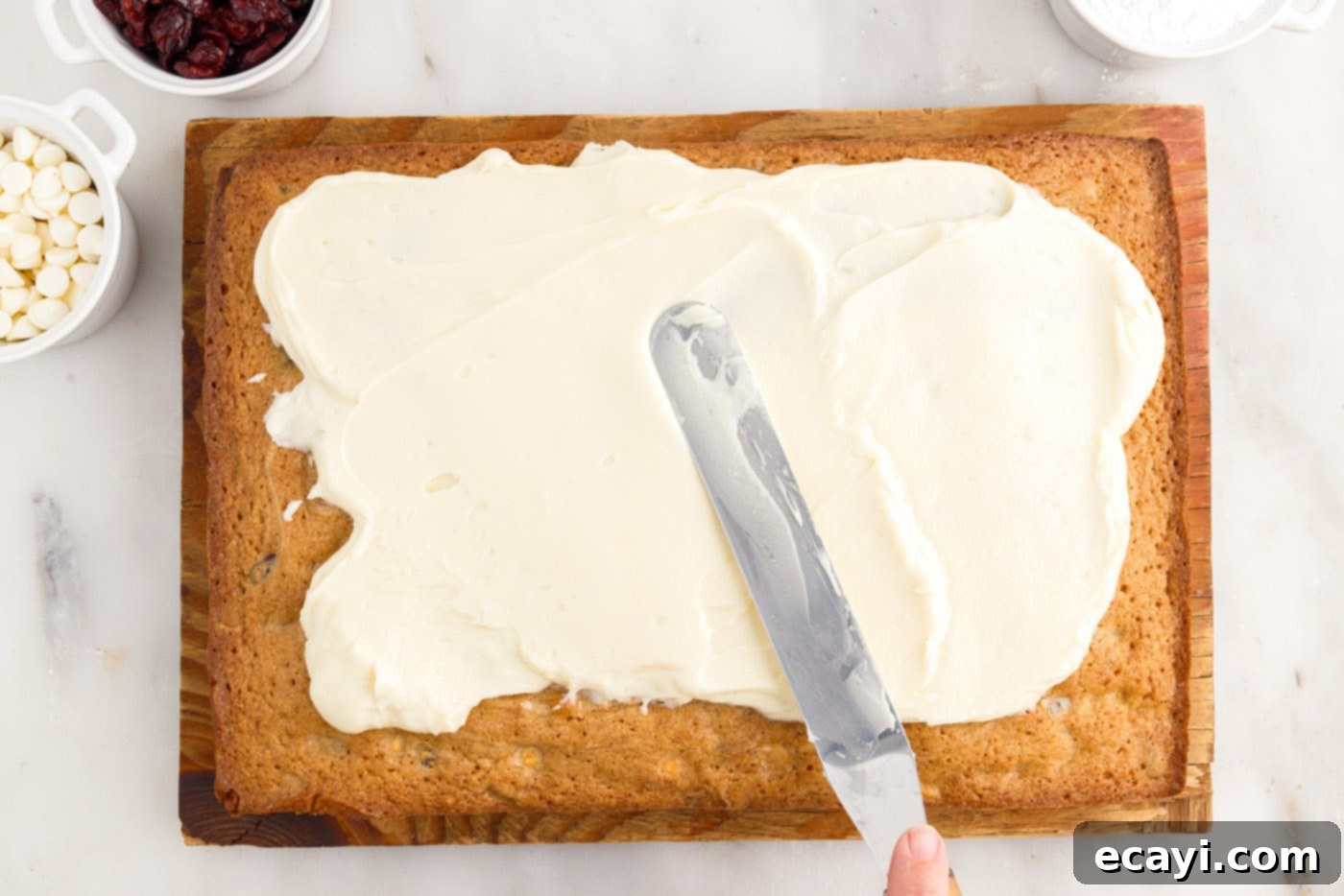 Dreamy Cranberry Squares 15 Cream cheese frosting being spread evenly over the baked blondies