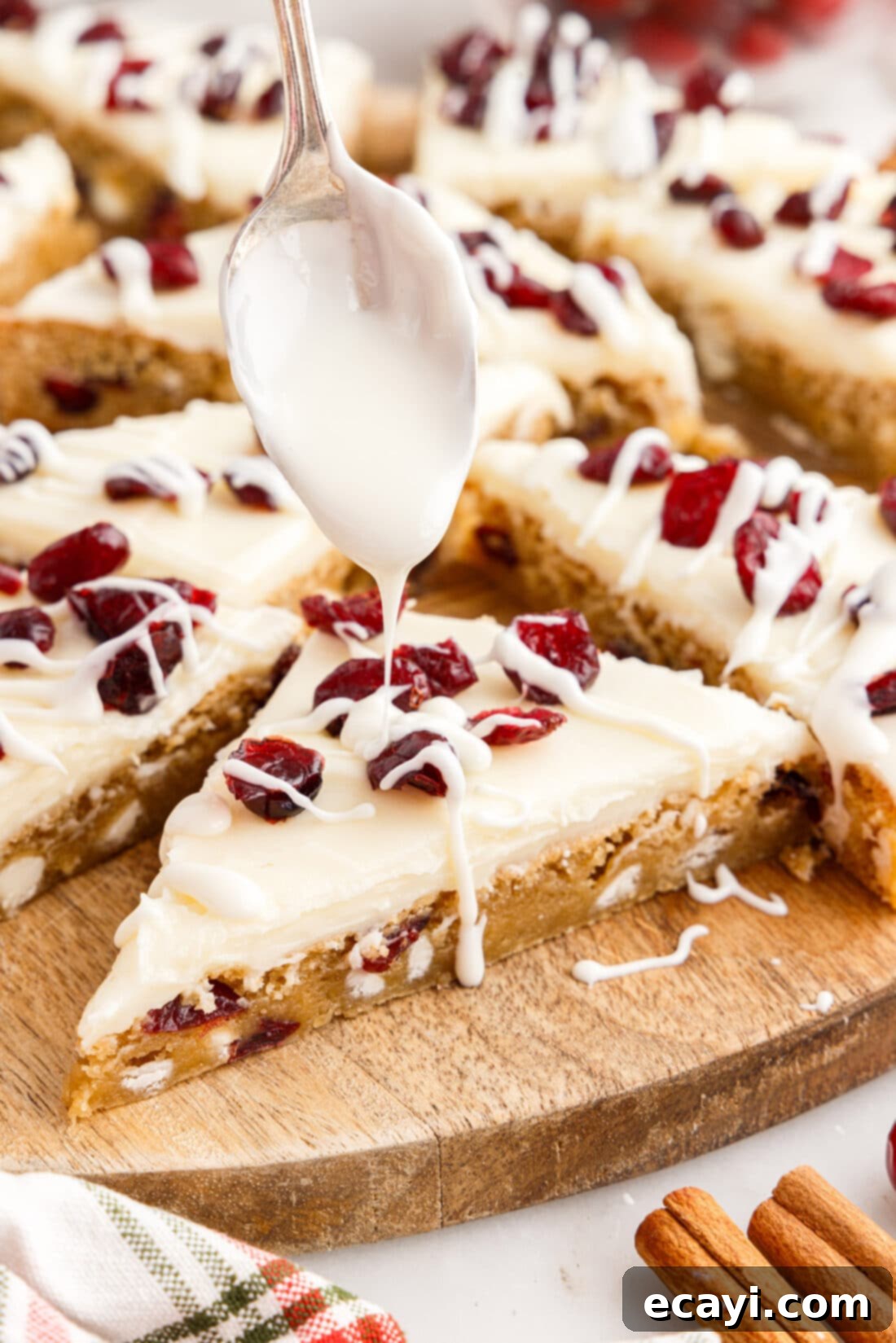 Dreamy Cranberry Squares 17 White chocolate being drizzled over a Cranberry Bliss Bar triangle