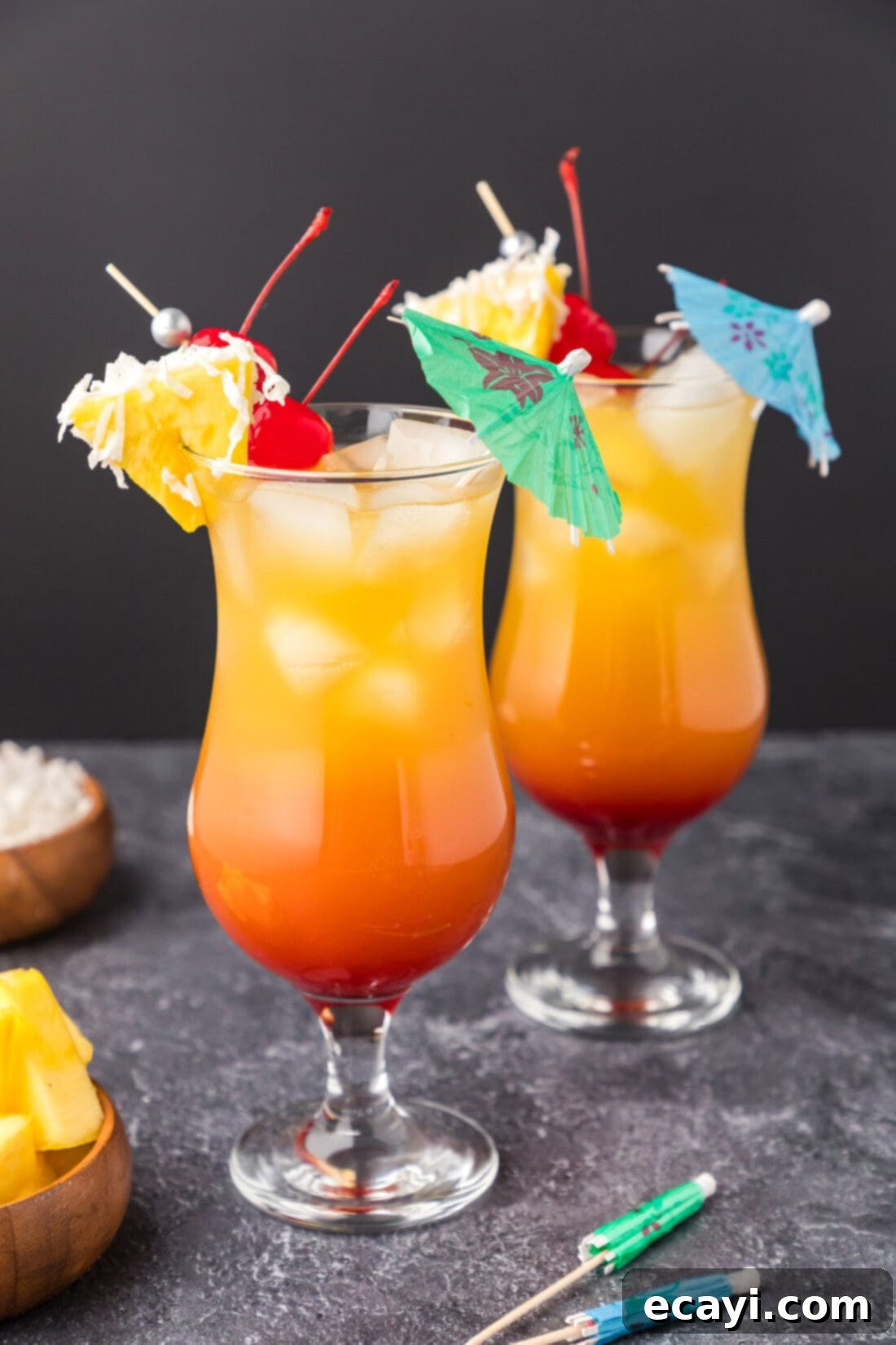 Malibu's Golden Hour 2 Two Malibu Sunset cocktails garnished with a pineapple wedge, cherry and umbrella