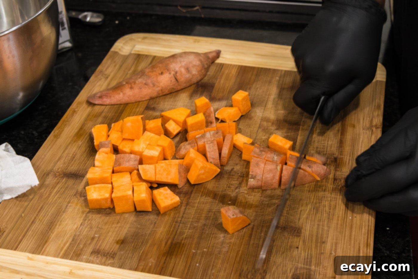The Ultimate Roasted Sweet Potatoes 5 dicing sweet potatoes with a knife on a cutting board